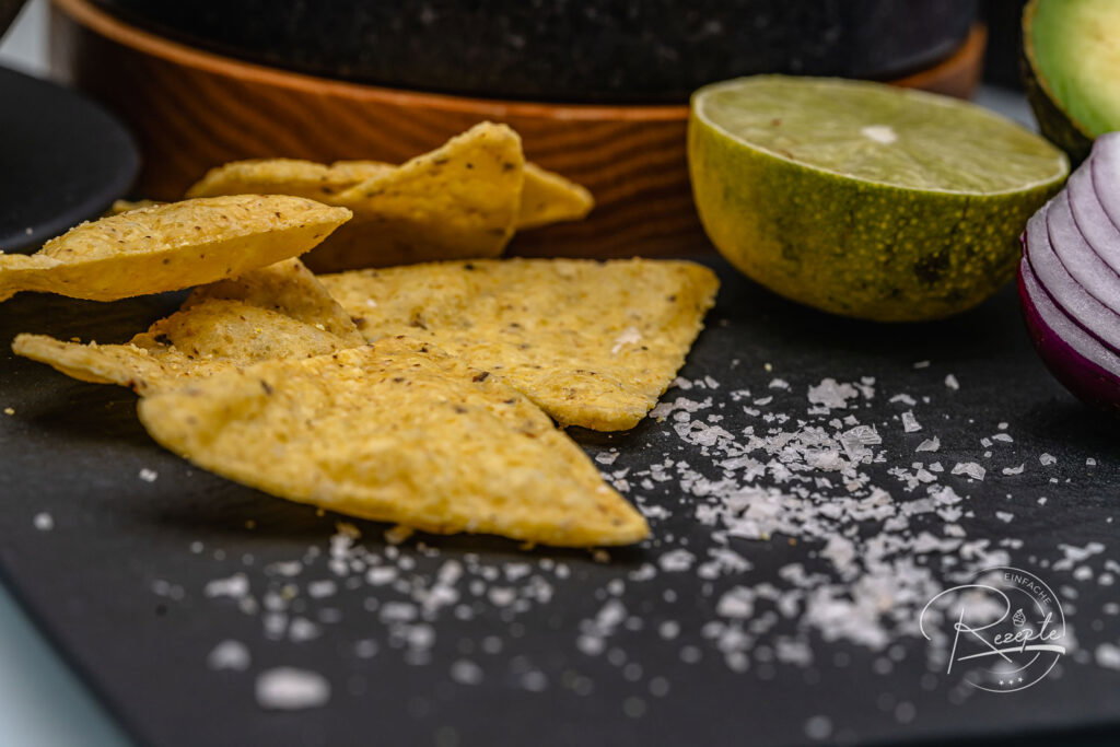 Tortilla-Chips mit Salzflocken auf Schieferplatte als Beilage zum Guacamole Rezept