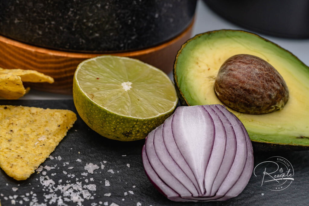 Frische Zutaten für das Guacamole Rezept: halbierte Avocado, Limette und rote Zwiebel