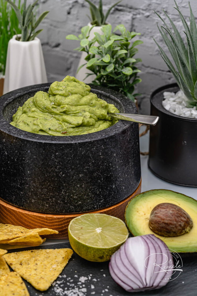 Steinmörser voll cremigem Dip mit Avocado, Limette, Zwiebel und Chips – Guacamole Rezept