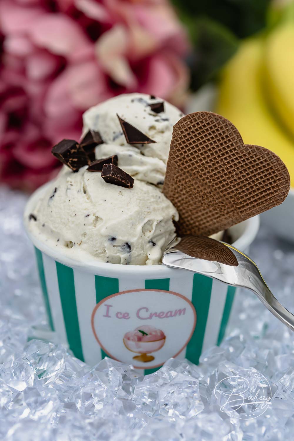 Nahaufnahme von Bananen Eis mit Schokoladenstücken und Schokowaffel-Herz im Eisbecher auf Crushed Ice