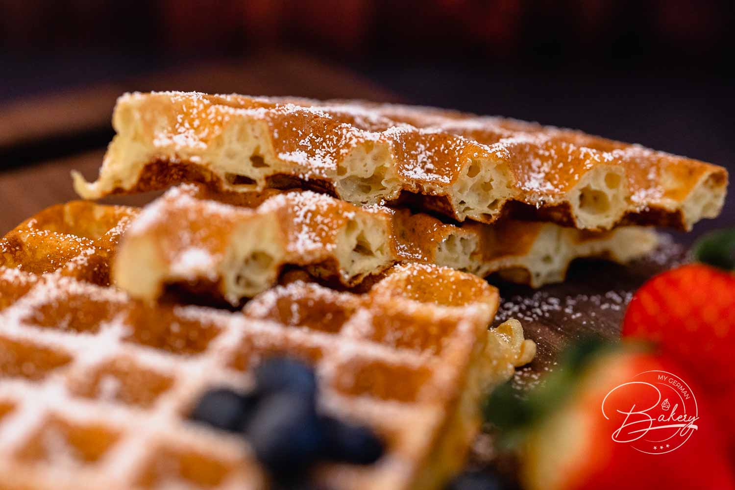 Aufgebrochene belgische Waffeln in Nahaufnahme mit luftiger Krume und feinem Puderzucker