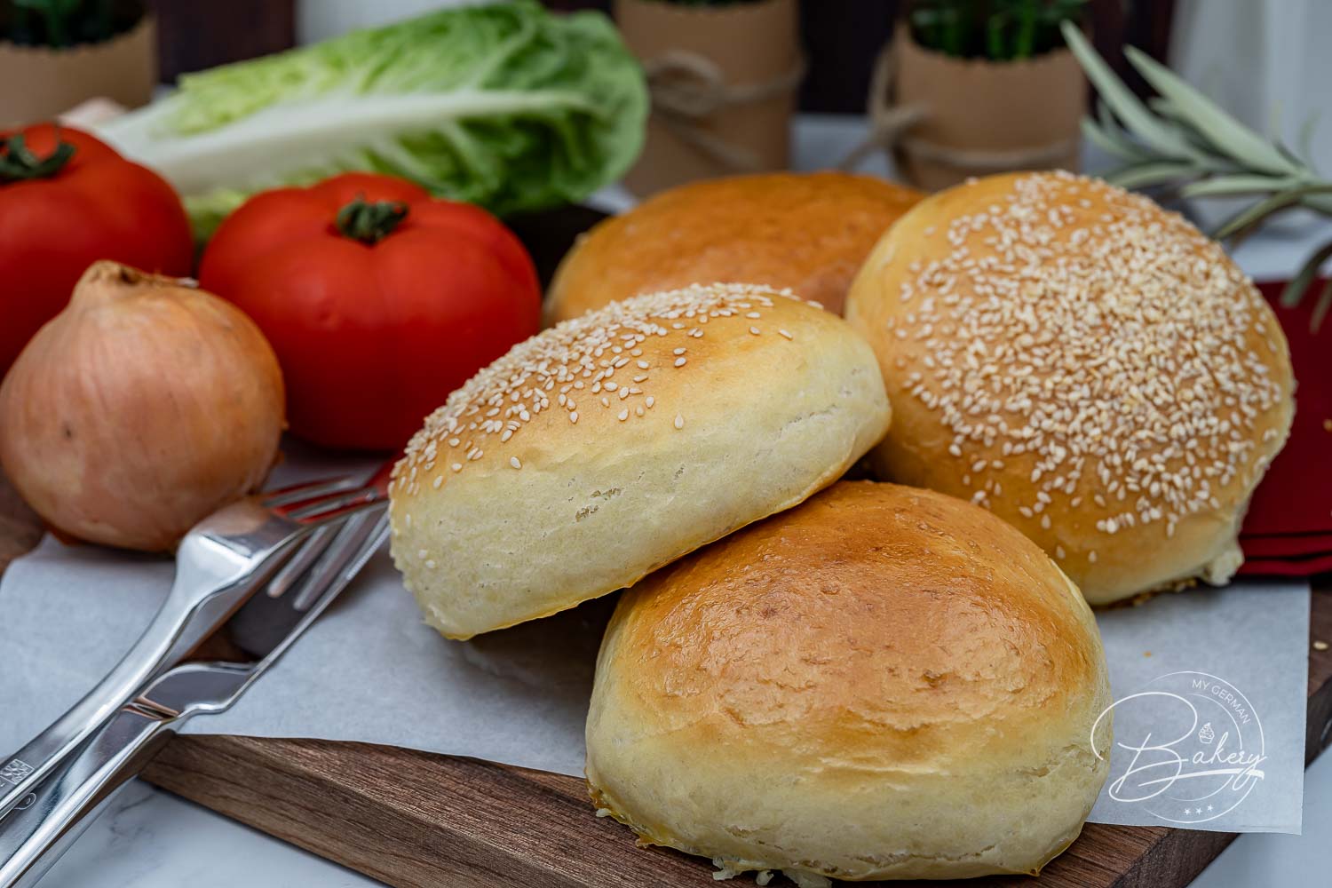 Brioche Burger Buns auf Backpapier, eine Hälfte mit Sesam, die andere ohne