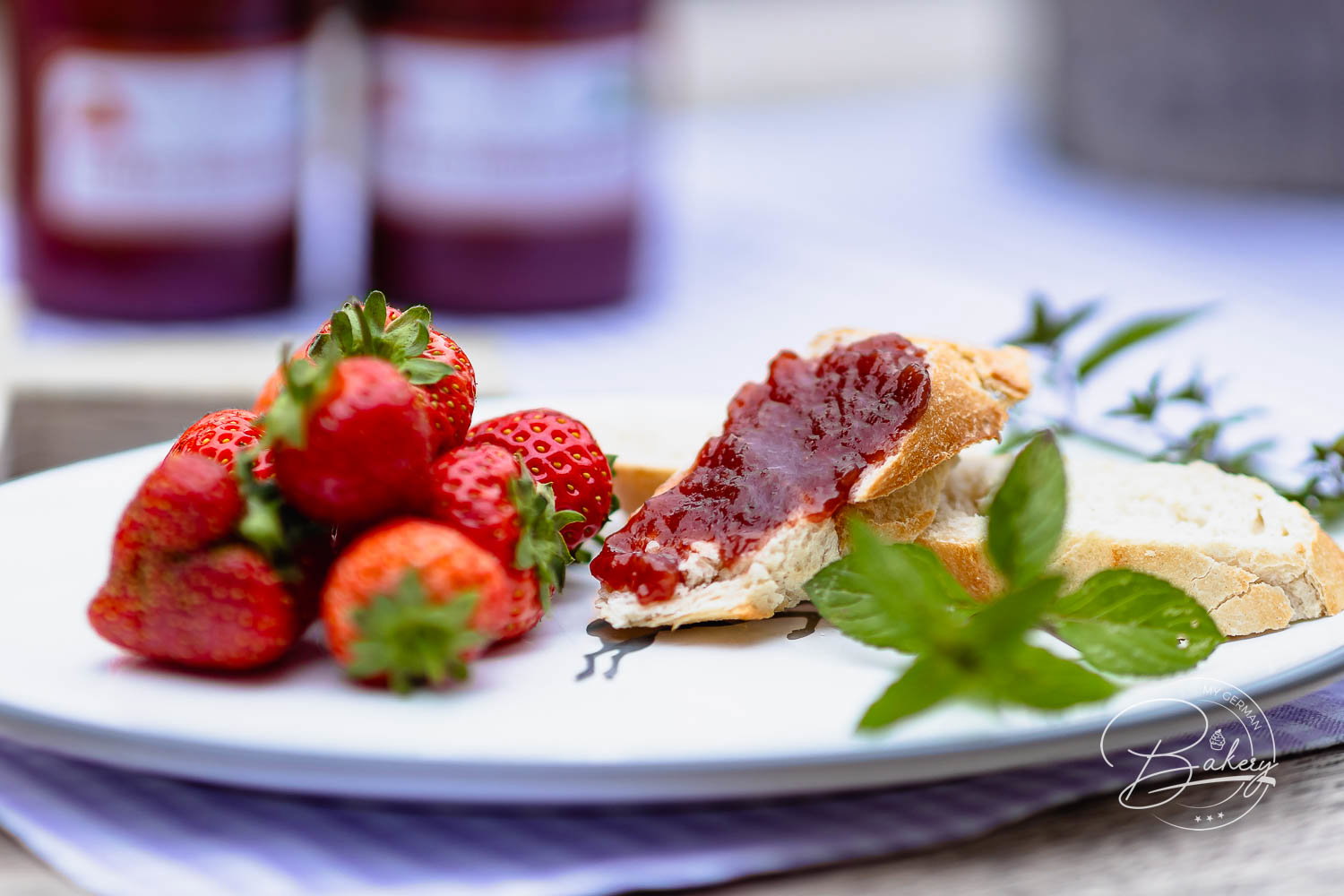 Frische Erdbeeren und Baguette mit selbst gemachter Erdbeermarmelade auf weißem Teller