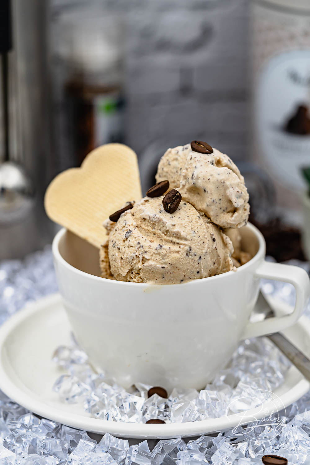 Kaffee Eis Kugeln in weißer Tasse auf Eiswürfeln, mit Kaffeebohnen und Waffelherz serviert