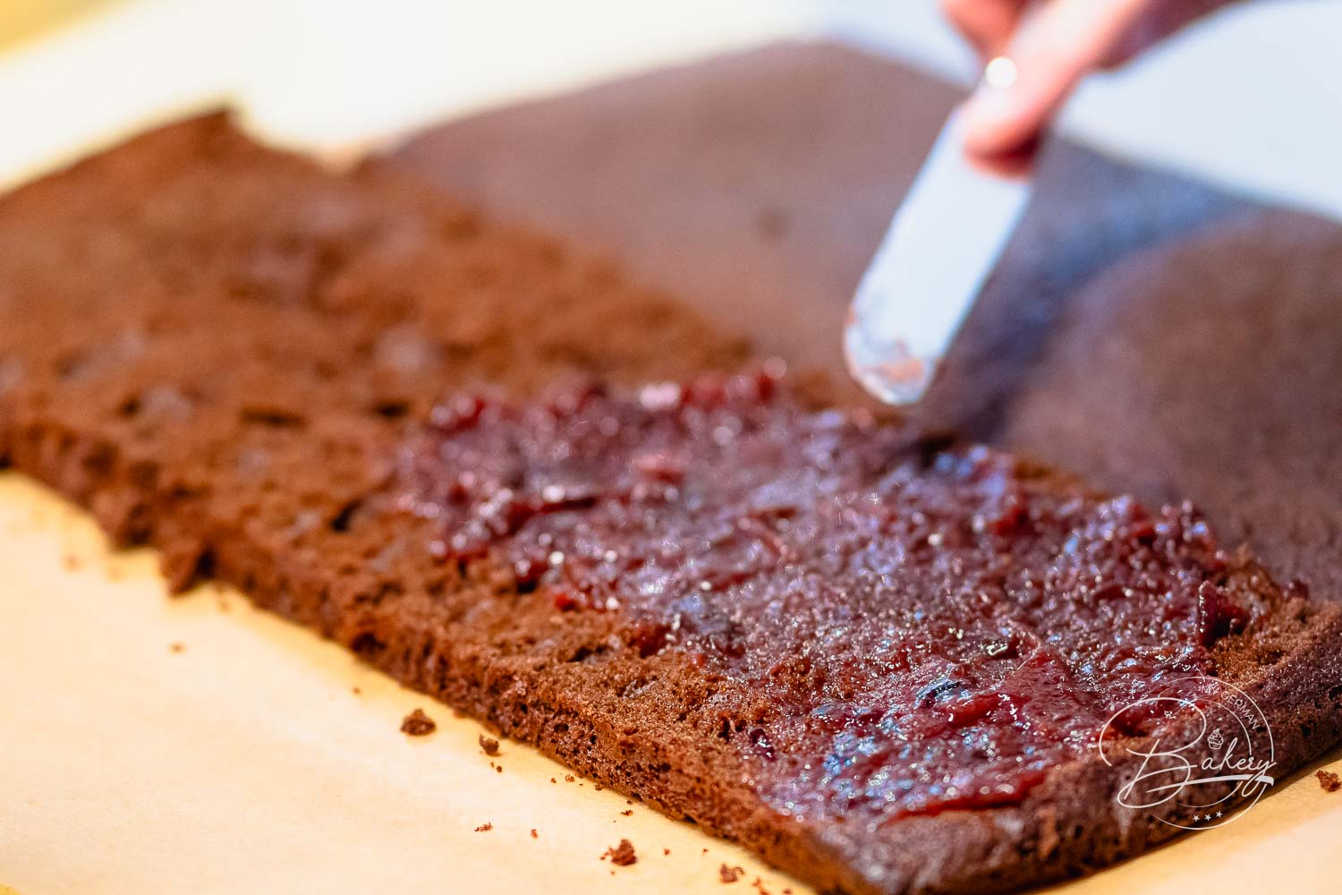Marmelade wird mit dem Messer auf den aufgeschnittenen Boden der Lebkuchen-Brownies gestrichen