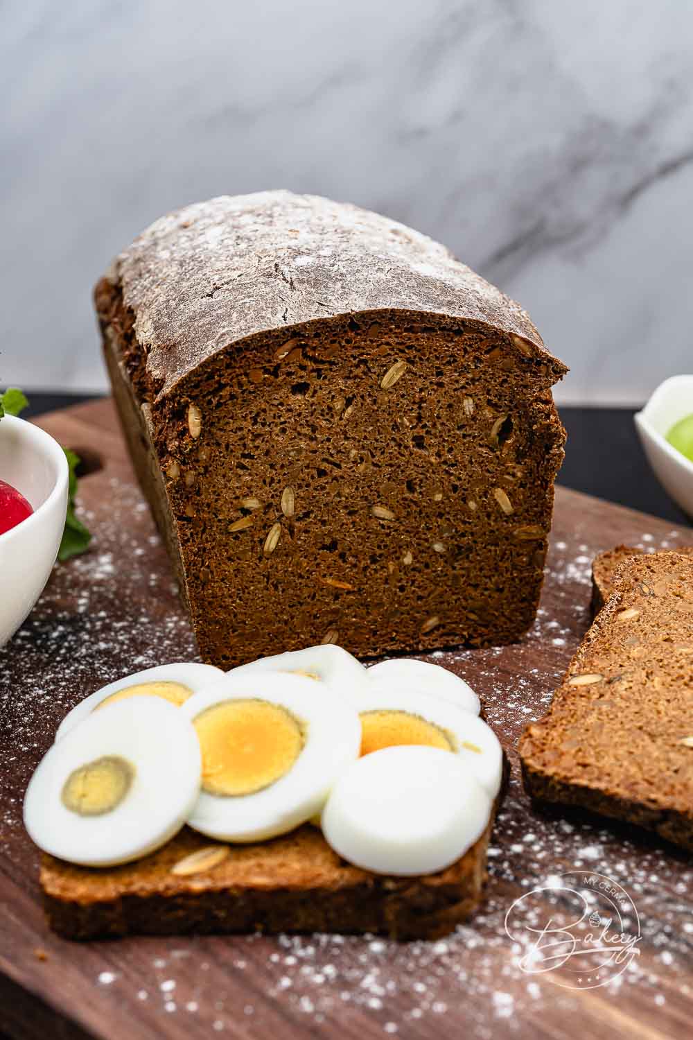 Detailaufnahme des dunklen Schwarzbrot-Laibs mit bemehlter Kruste und sichtbaren Körnern – Vollkornbrot Rezept mit Roggenschrot