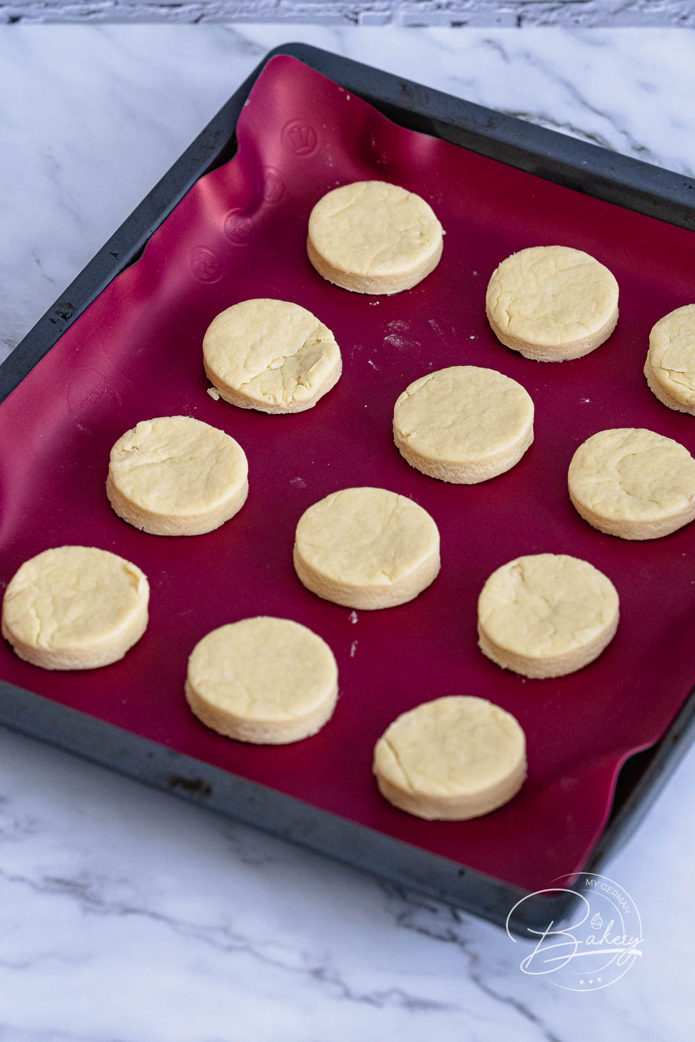Zwölf runde ausgestochene Scones roh auf dem Backblech vor dem Backen