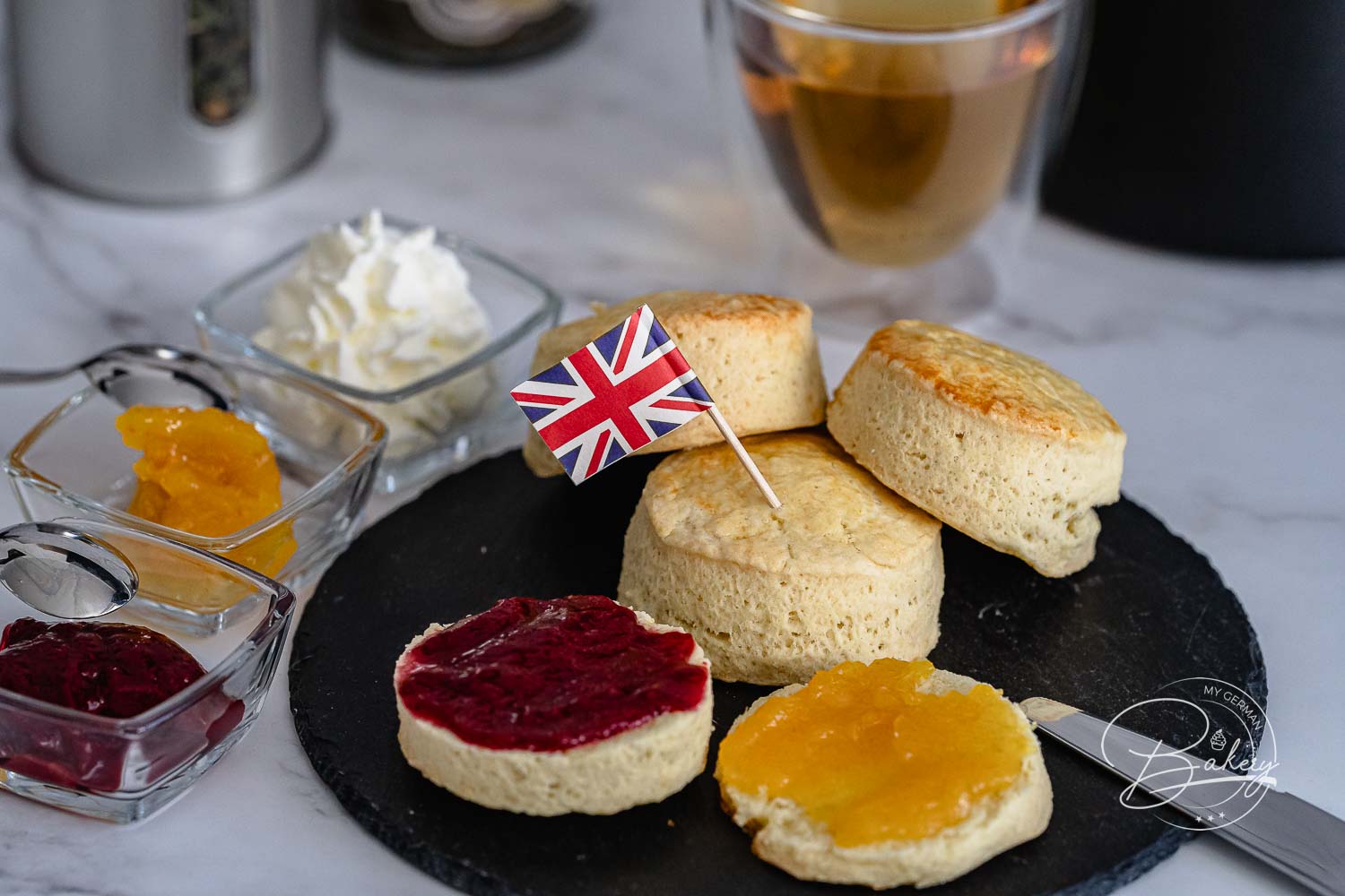 Frisch gebackene Scones mit Union-Jack-Fähnchen, Marmelade und Sahne zur Tea Time