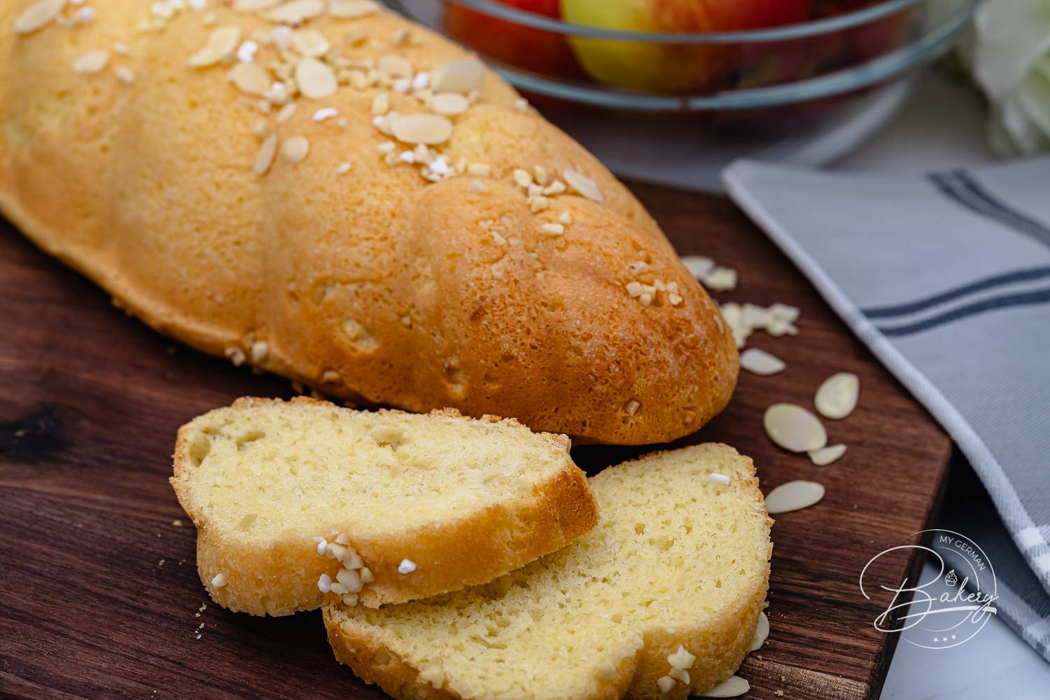 Goldbraun gebackenes Stutenbrot mit Mandelblättchen und Hagelzucker, angeschnitten auf einem Holzbrett