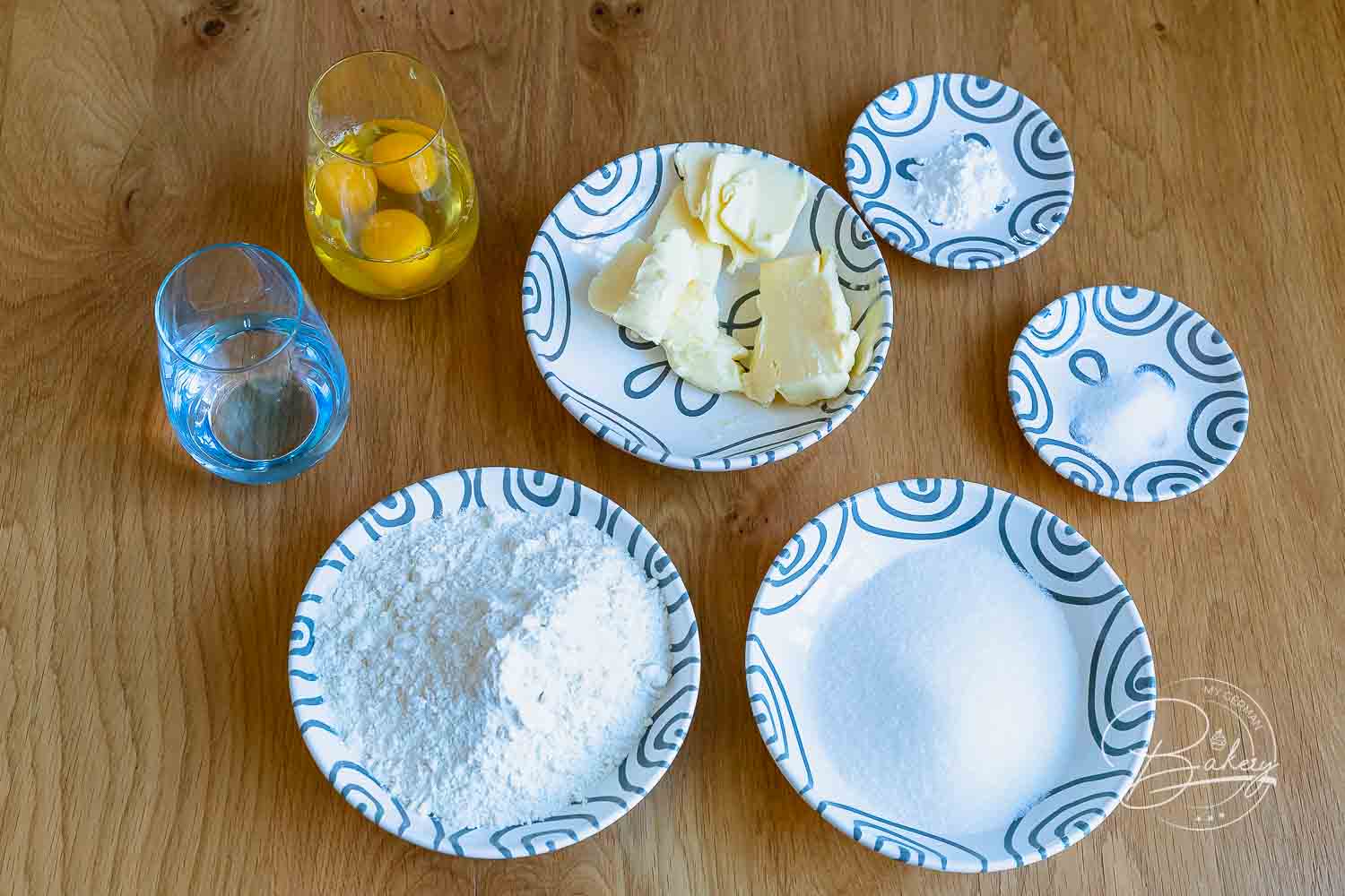 Abgewogene Zutaten für Waffeln ohne Milch: Mehl, Zucker, Butter, Eier und Sprudelwasser