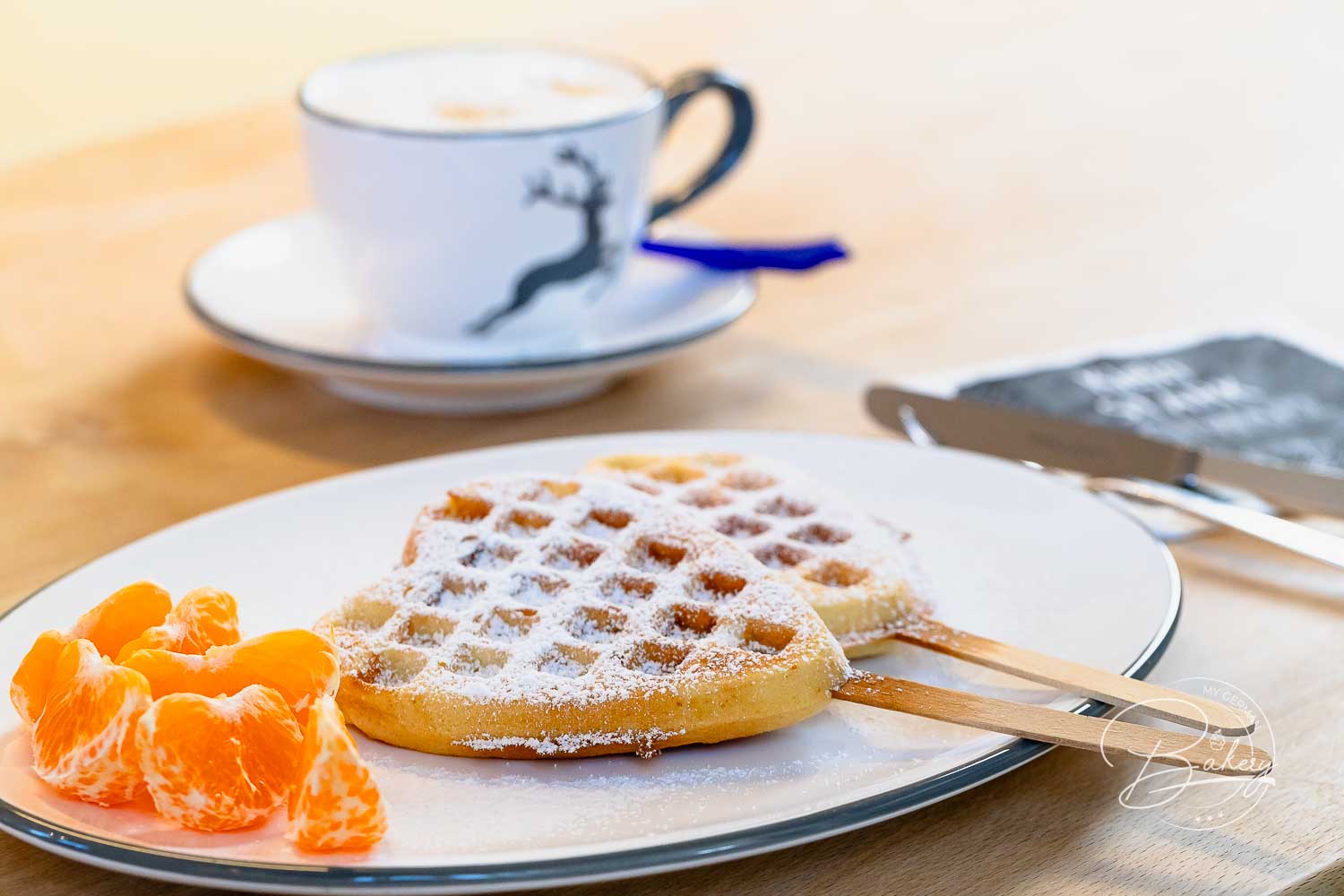 Zwei Herzwaffeln am Stiel mit Puderzucker und Mandarinen – fertige Waffeln ohne Milch